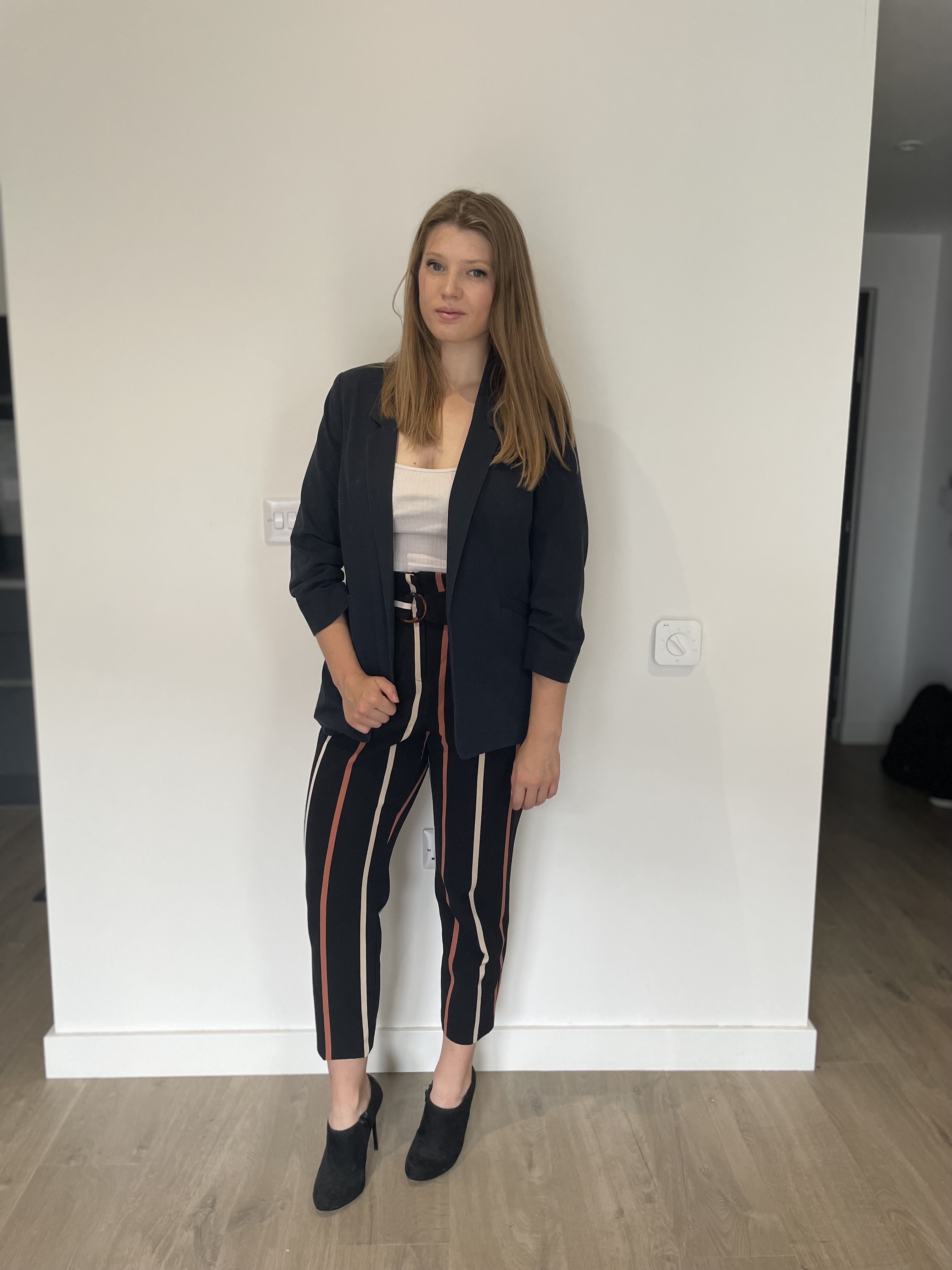 Outfit is tailored pinstripe trousers with a blue blazer and black heels.