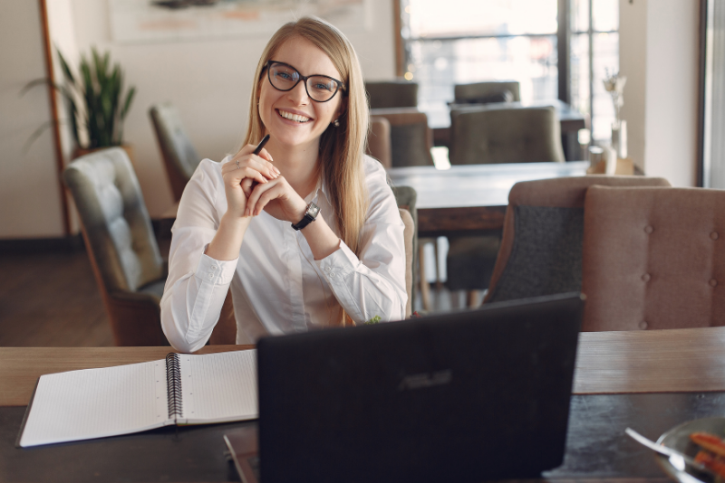 An intern sat at a work desk smiling.